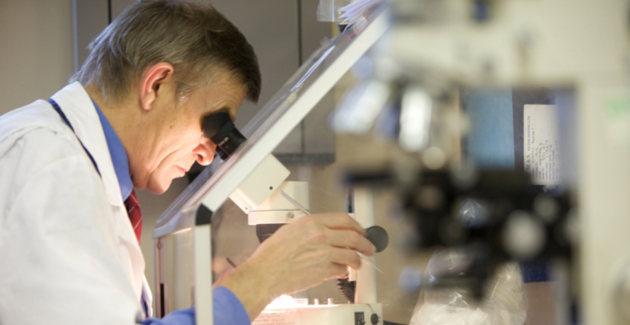 Asbestos analyst and microscope Asbestos analyst looking down a microscope testing a sample